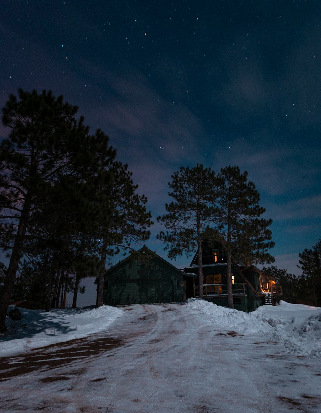 brown wooden house in the middle of snow covered field during night time