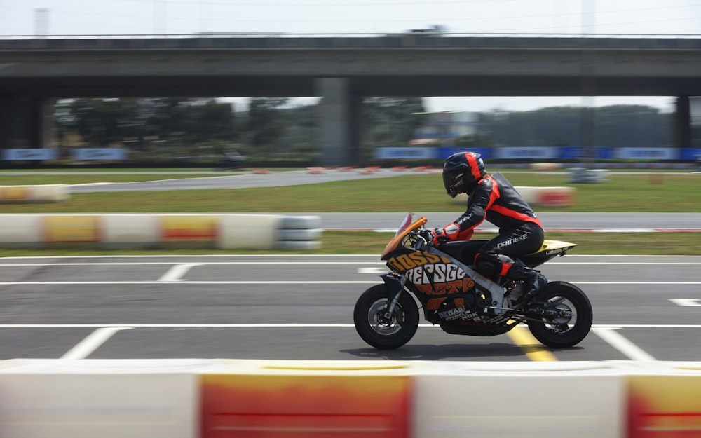 man in orange and black jacket riding orange and black sports bike