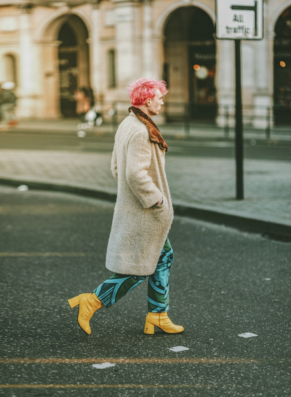 Chica con bata blanca y jeans de mezclilla azul caminando en la acera durante el día