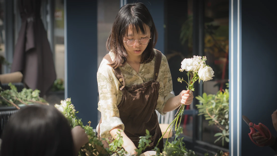 Floristė salone renka puokštę iš baltų gėlių