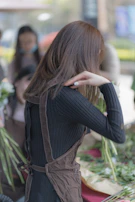 A professional domestic staff member arranging fresh flowers in a bright, tidy kitchen.