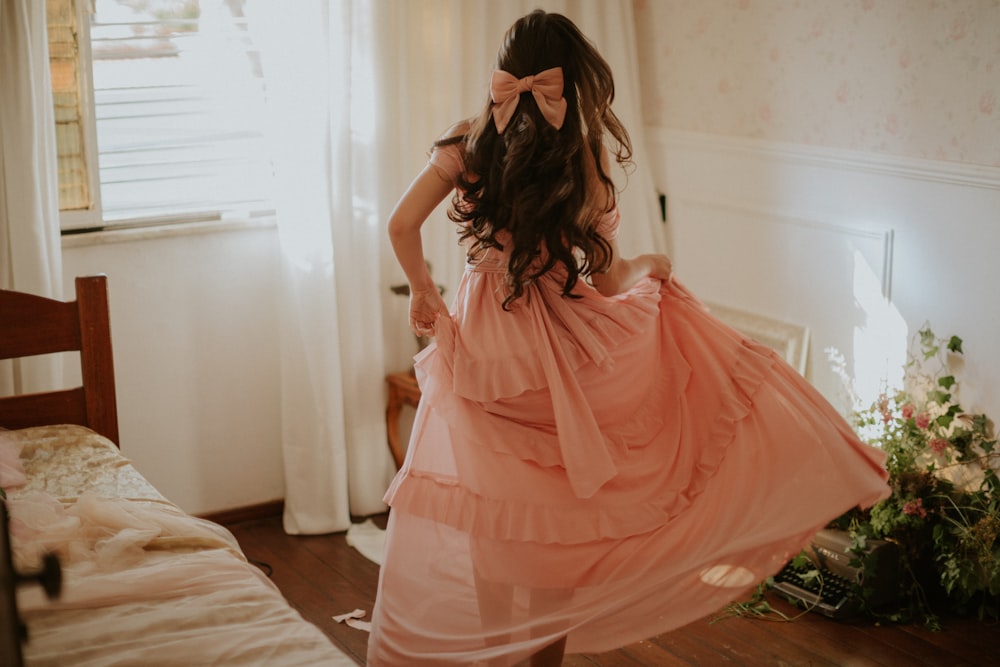 femme en robe rose debout sur le lit