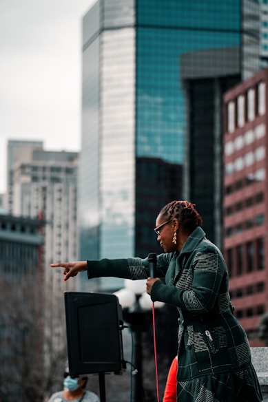 woman in green jacket standing near building during daytime