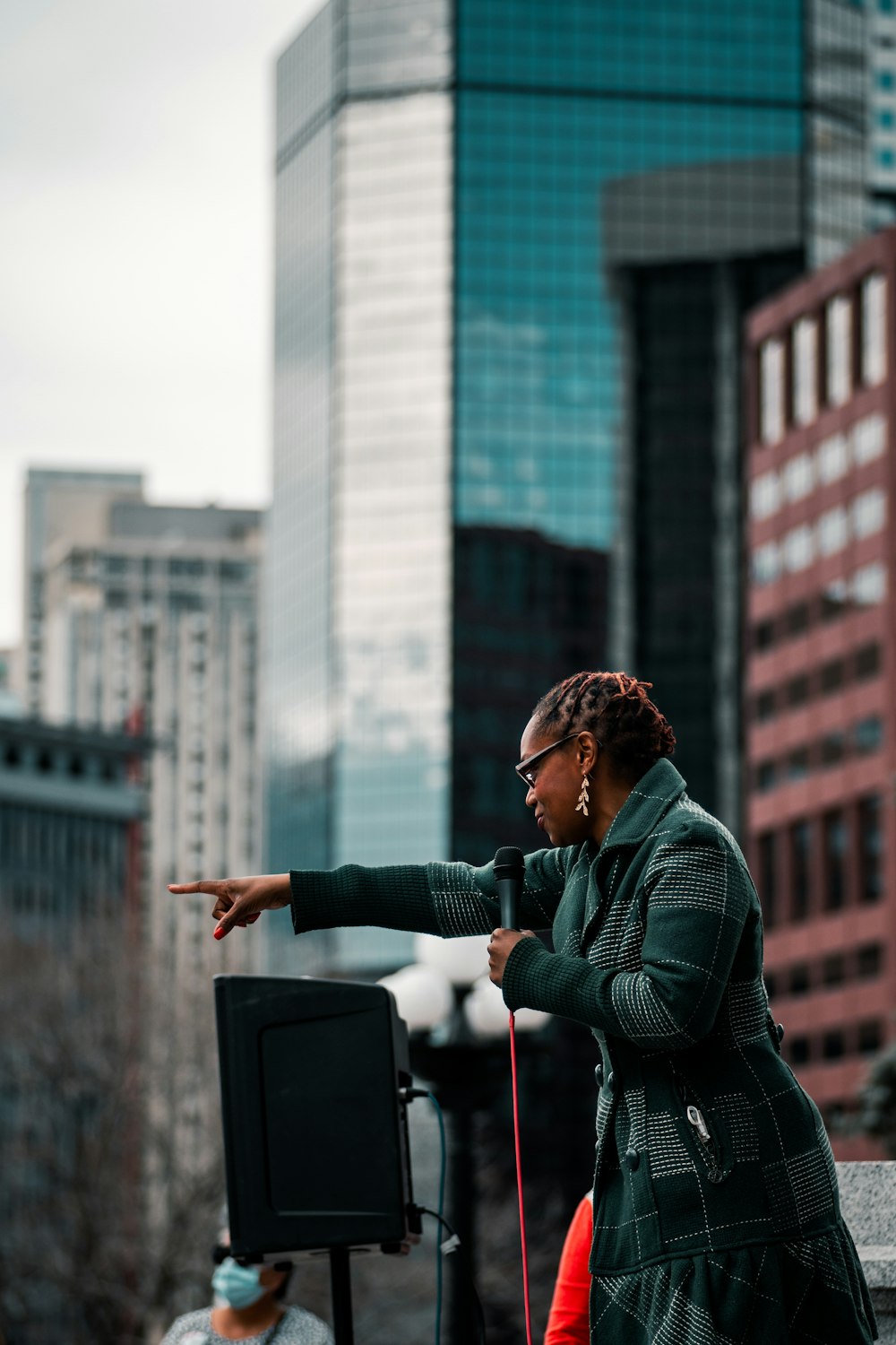 낮 동안 건물 근처에 서 있는 녹색 재킷을 입은 여자