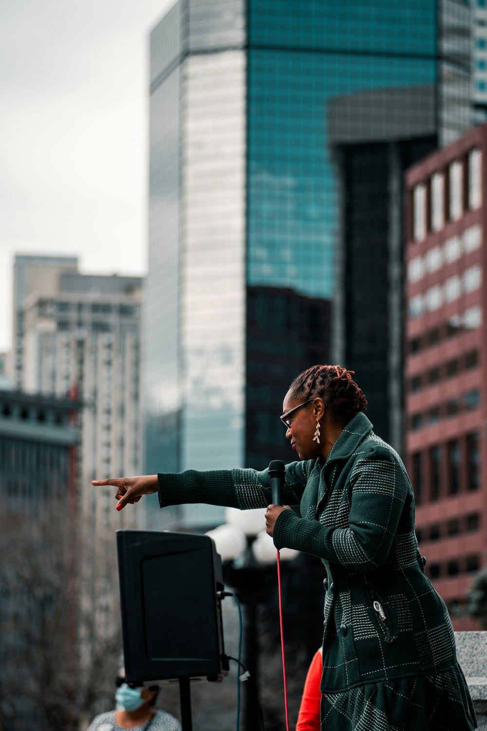 woman in green jacket standing near building during daytime