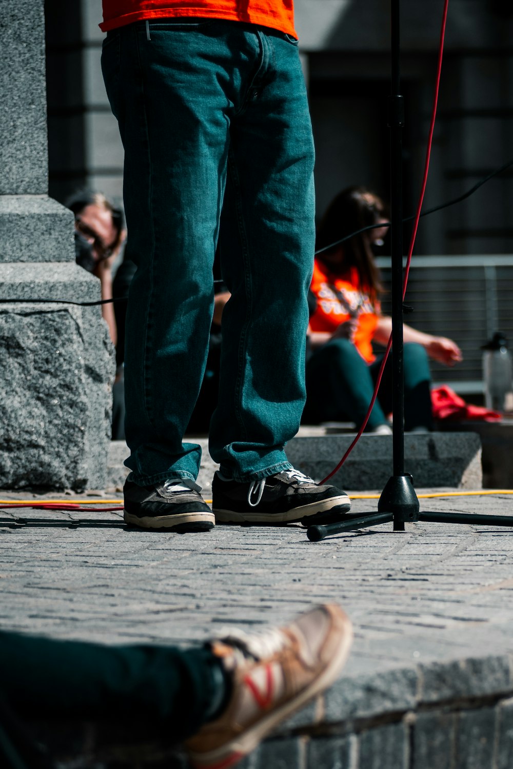 person in blue denim jeans and black sneakers standing on brown wooden plank during daytime