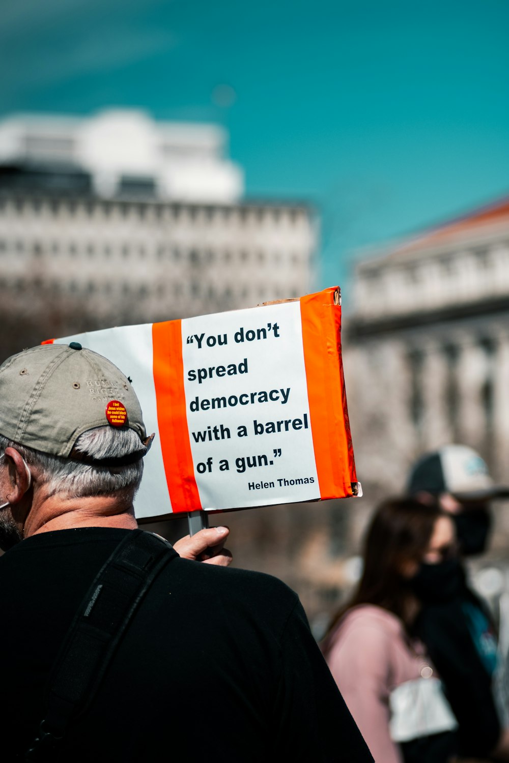 man in black jacket holding white and orange signage during daytime