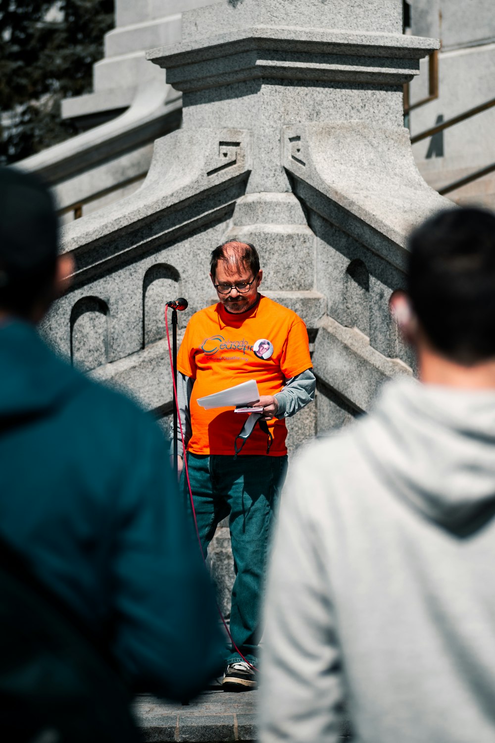 Hombre con camiseta naranja de cuello redondo de pie junto a una mujer con hiyab blanco