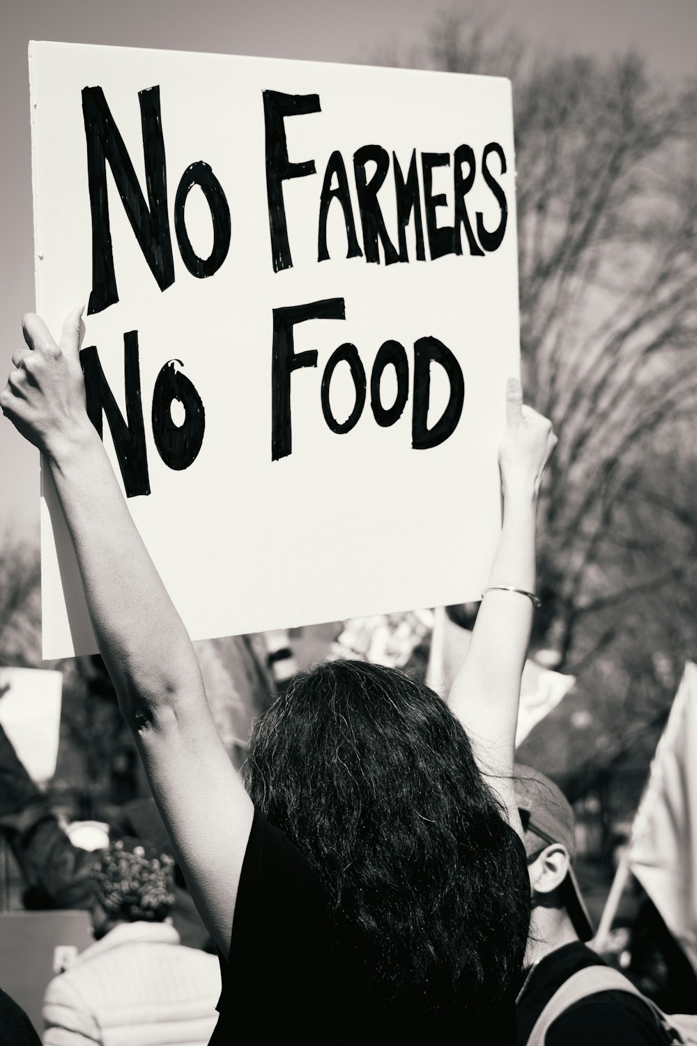 a person holding a sign that says no farmers no food