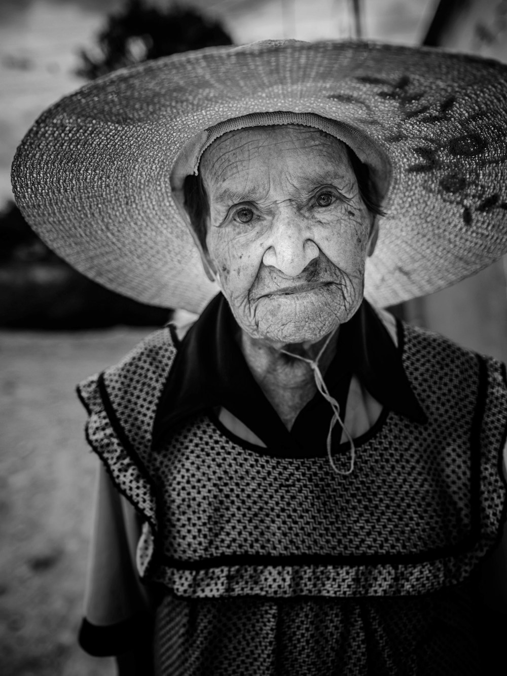 Foto en escala de grises de un hombre con sombrero y camisa a cuadros