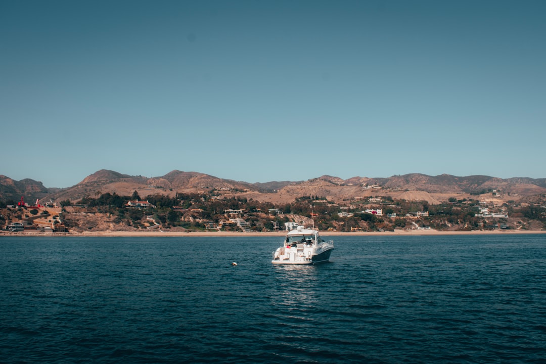 white boat on sea near mountain during daytime