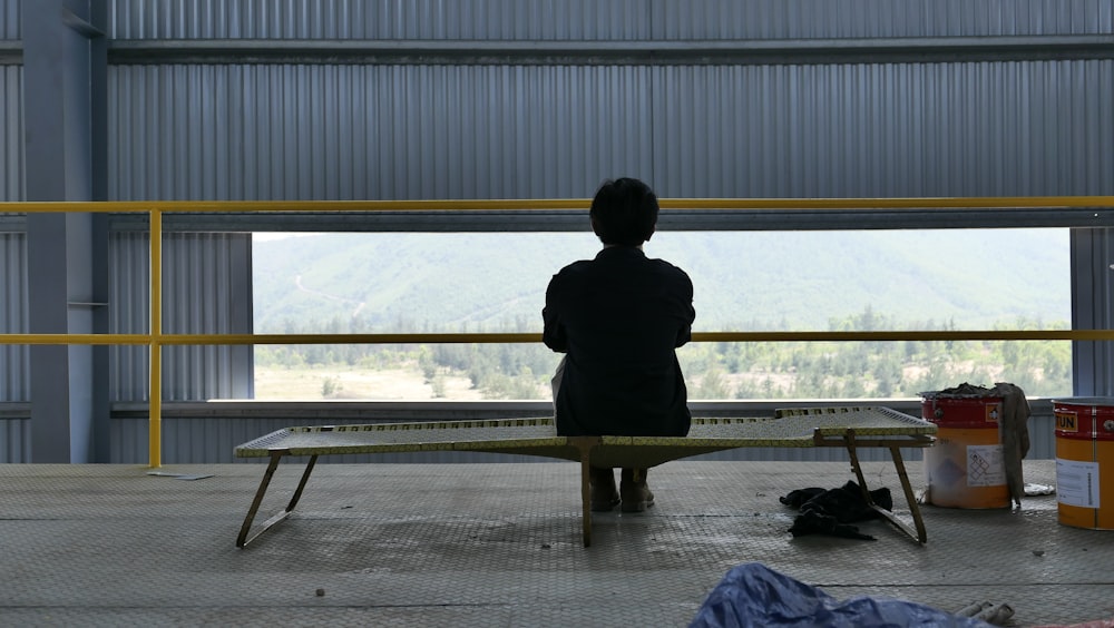 person in black coat sitting on bench