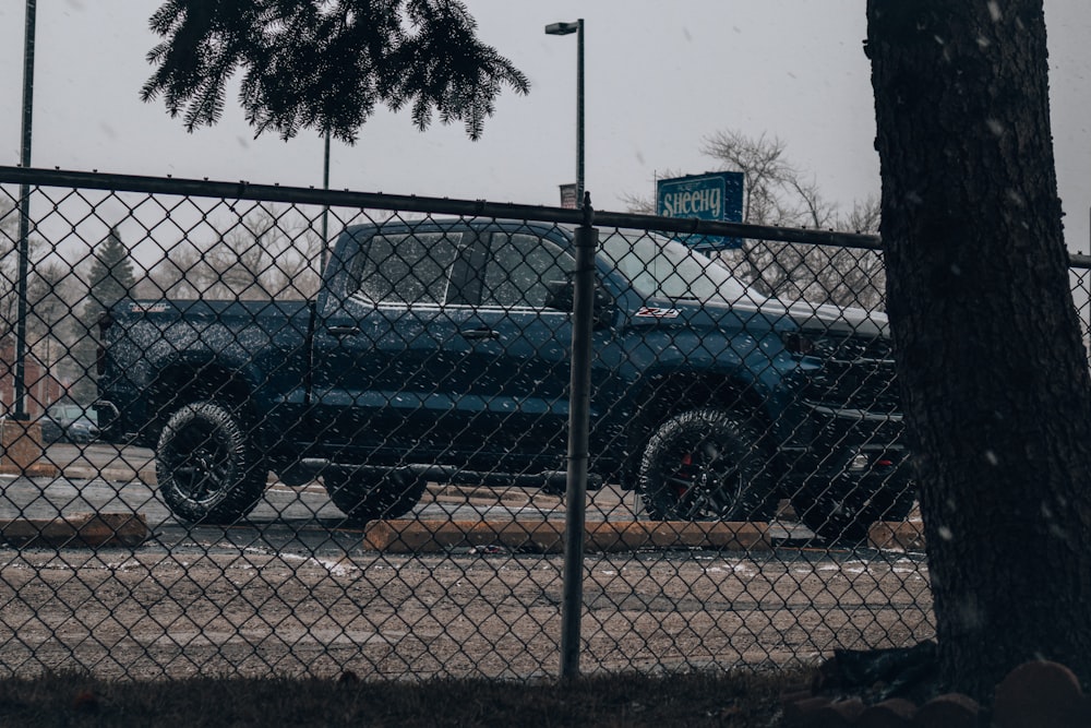 Schwarzer SUV tagsüber neben grauem Metallzaun geparkt