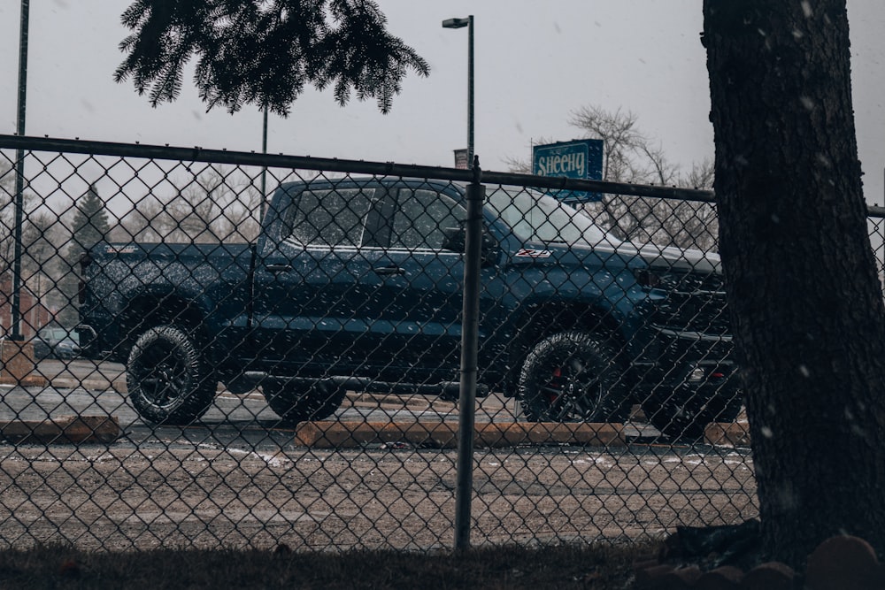 suv preto estacionado ao lado de cerca de metal cinza durante o dia