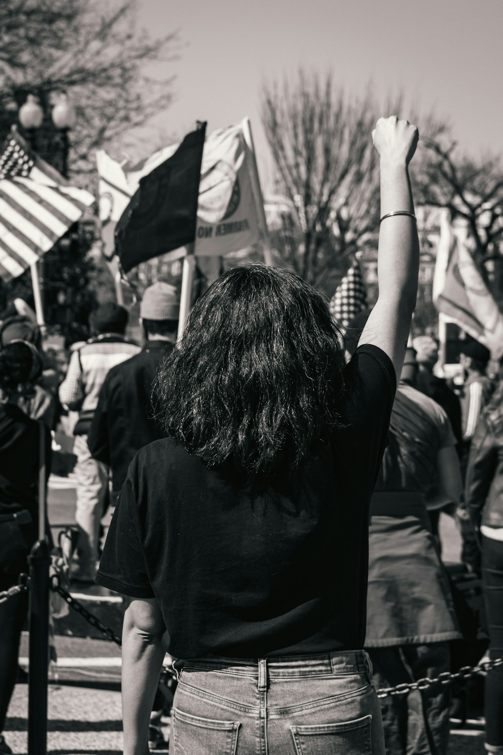 Foto in scala di grigi di donna in camicia nera che tiene bandiera