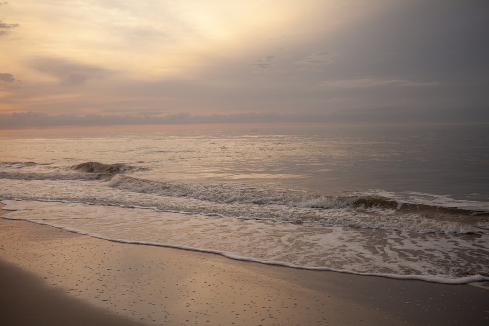 ocean waves crashing on shore during sunset