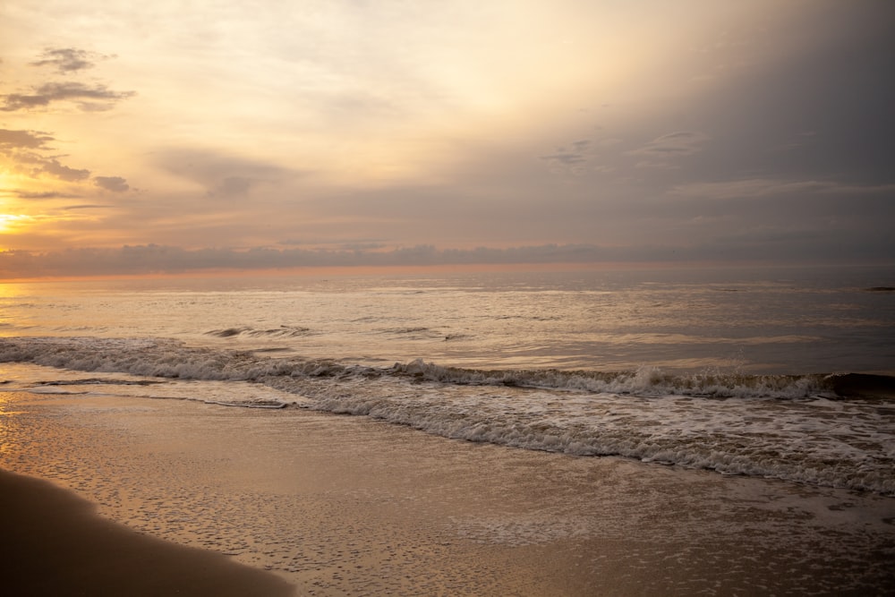 ocean waves crashing on shore during sunset