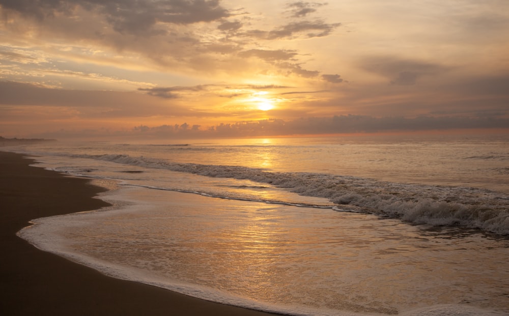 sea waves crashing on shore during sunset