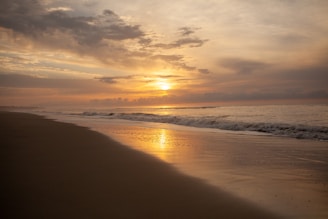 A peaceful beach at sunset with golden sand and gentle waves.