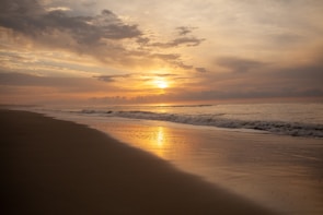 A serene beach at sunset with golden sands and gentle waves in a tropical paradise.