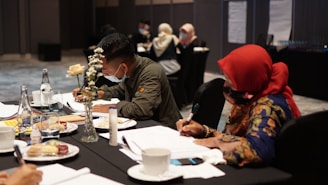 man in brown jacket sitting on chair in front of table