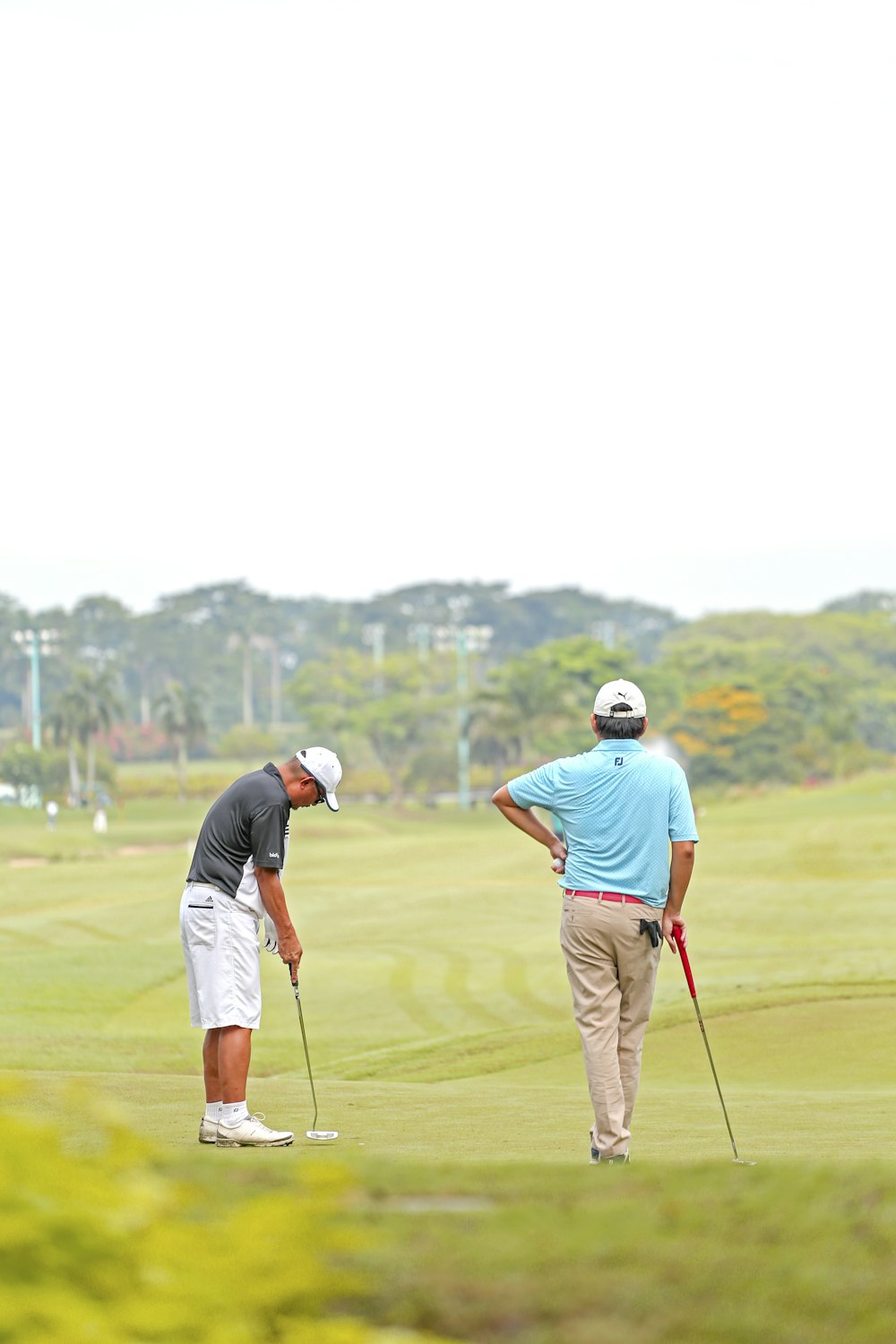 Hombre con camisa naranja y pantalones cortos azules jugando al golf durante el día