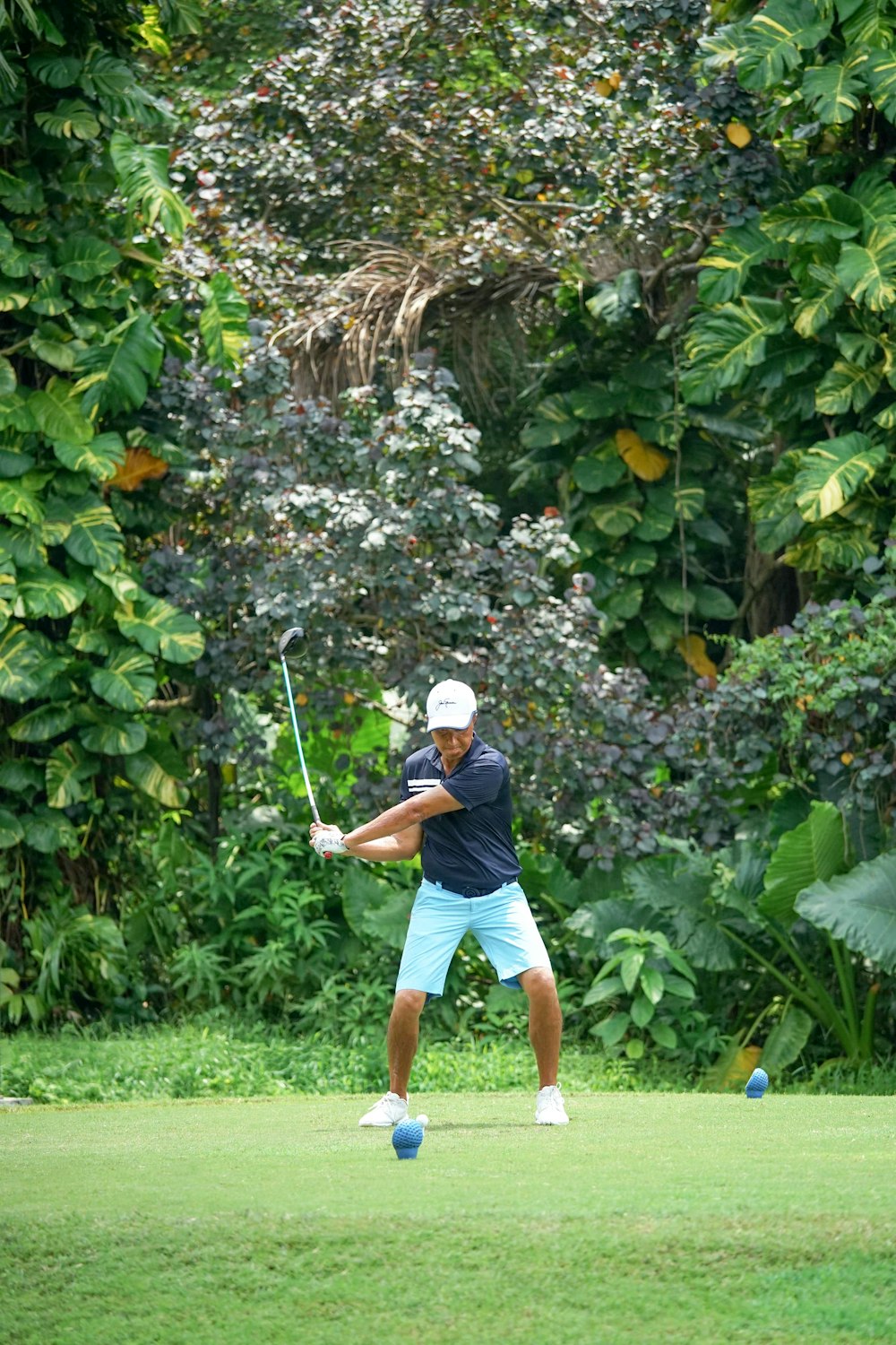 man in blue shirt and brown shorts playing golf during daytime