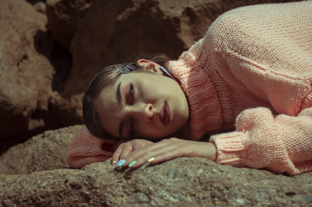 Mädchen im rosa Strickpullover auf dem Boden liegend