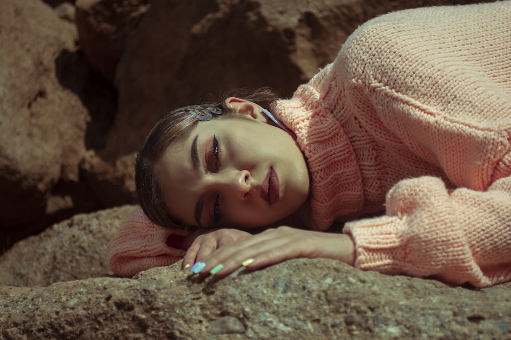 girl in pink knit sweater lying on ground