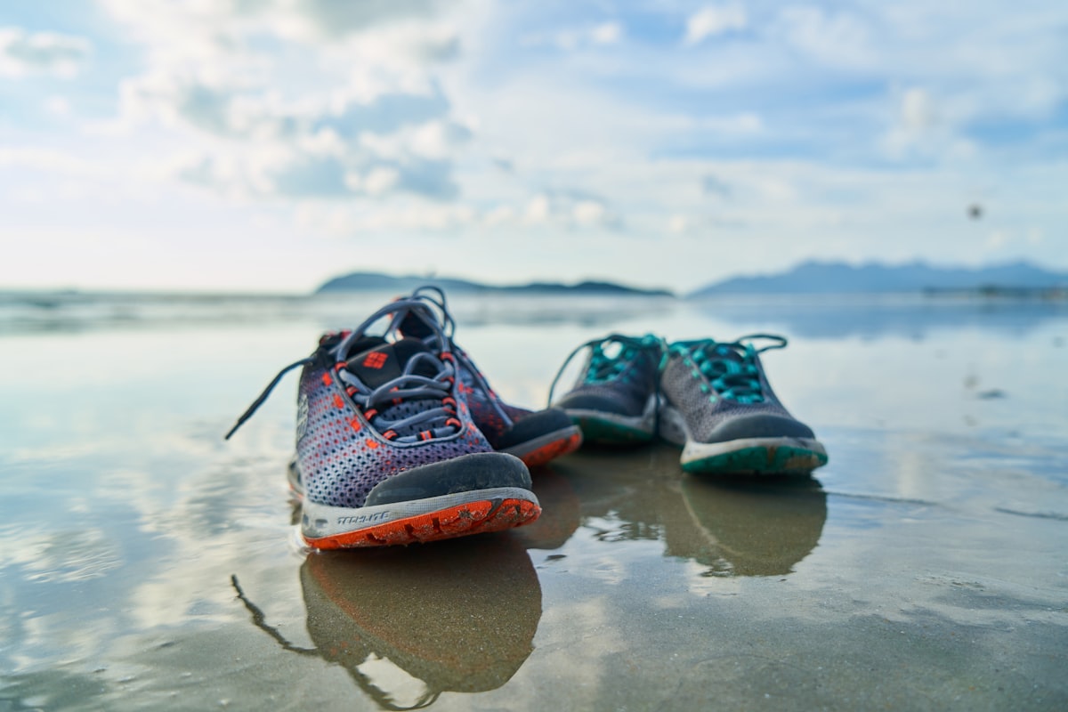 Blue and black athletic shoes on brown sand during daytime