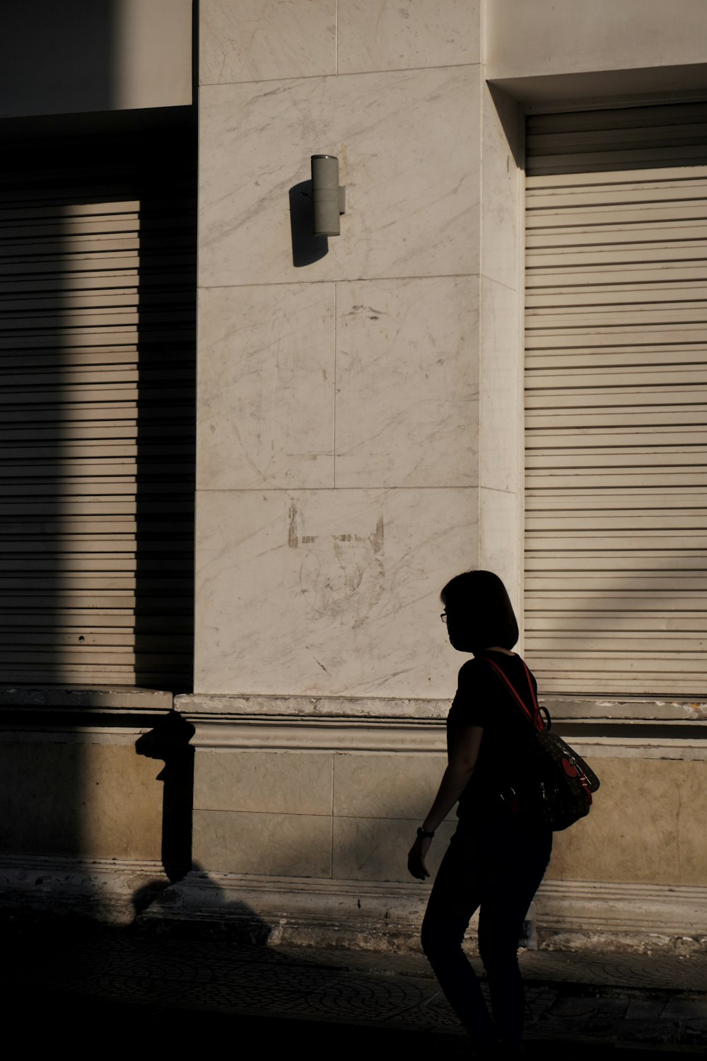 man in black shirt and black shorts walking on sidewalk