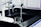 A laboratory workspace features a black countertop with a beaker partly filled with liquid. Above the beaker, there is laboratory equipment including faucets and dispensers. The environment appears sterile and clean, typical of a scientific or research setting.
