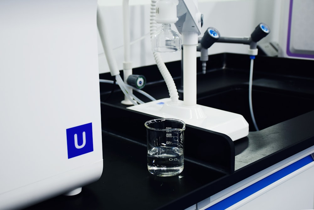 clear glass mug beside white and blue electric toothbrush