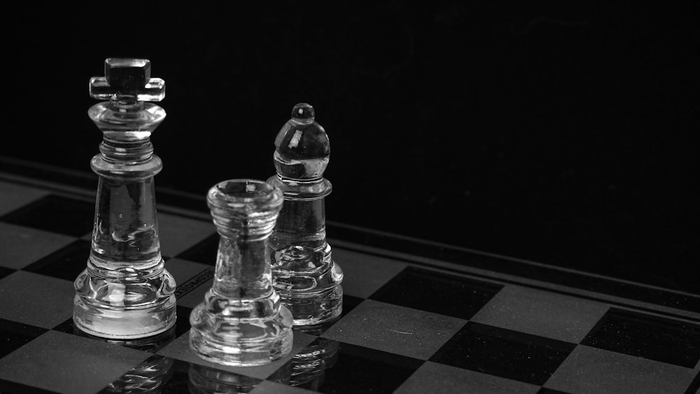 Schachfigur aus klarem Glas auf schwarz-weiß kariertem Tisch
