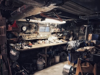 Wide shot of the workshop floor with scattered tools, a van in mid-repair, and dark charcoal walls