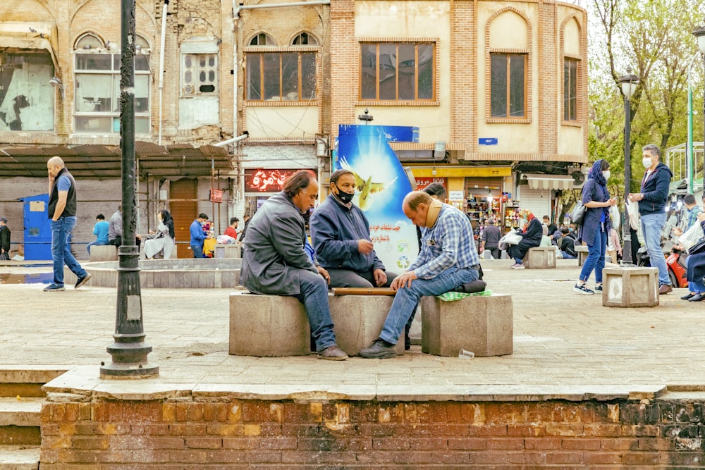 Hombre en jeans de mezclilla azul sentado en un banco de concreto gris durante el día