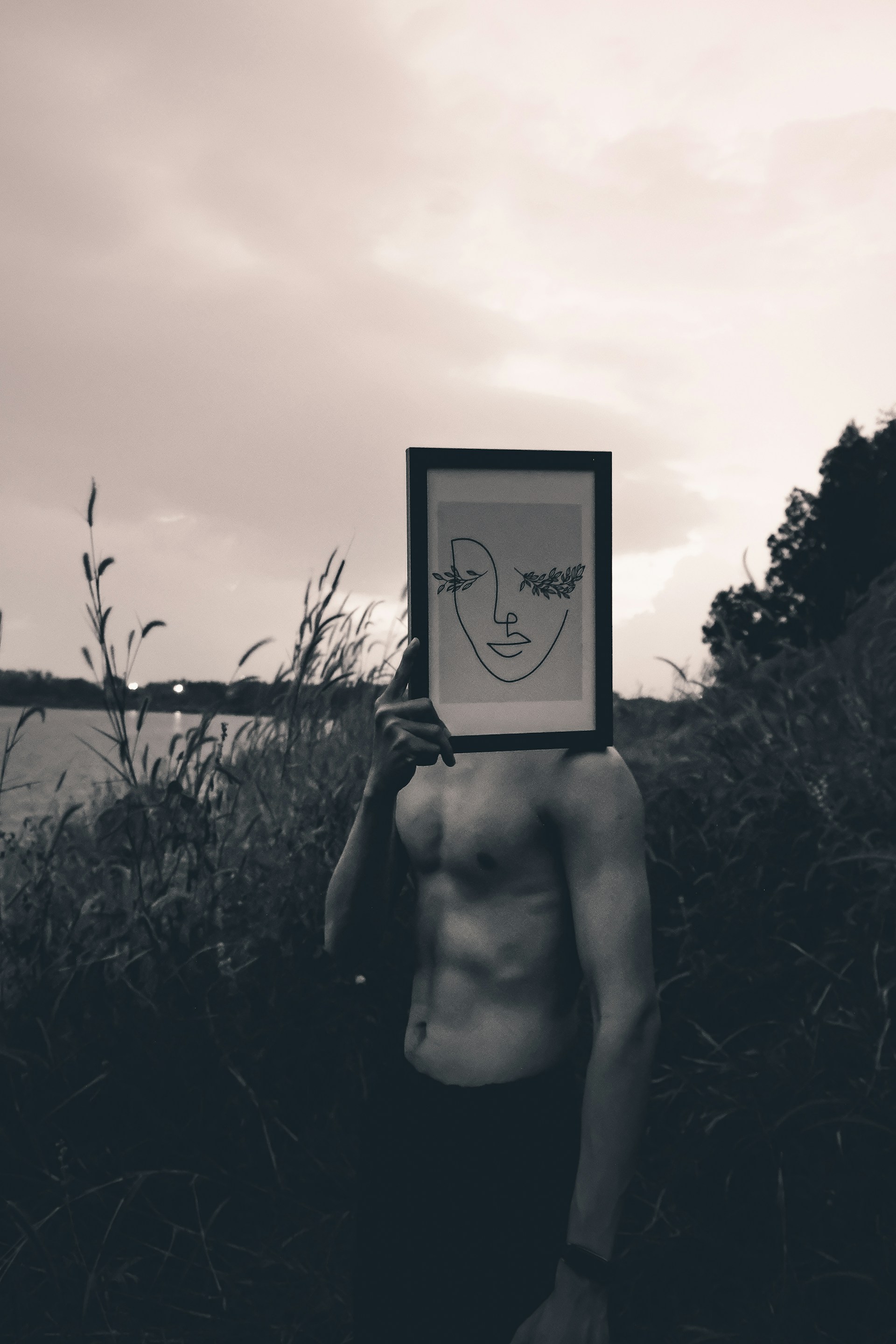 grayscale photo of naked woman holding black and white frame