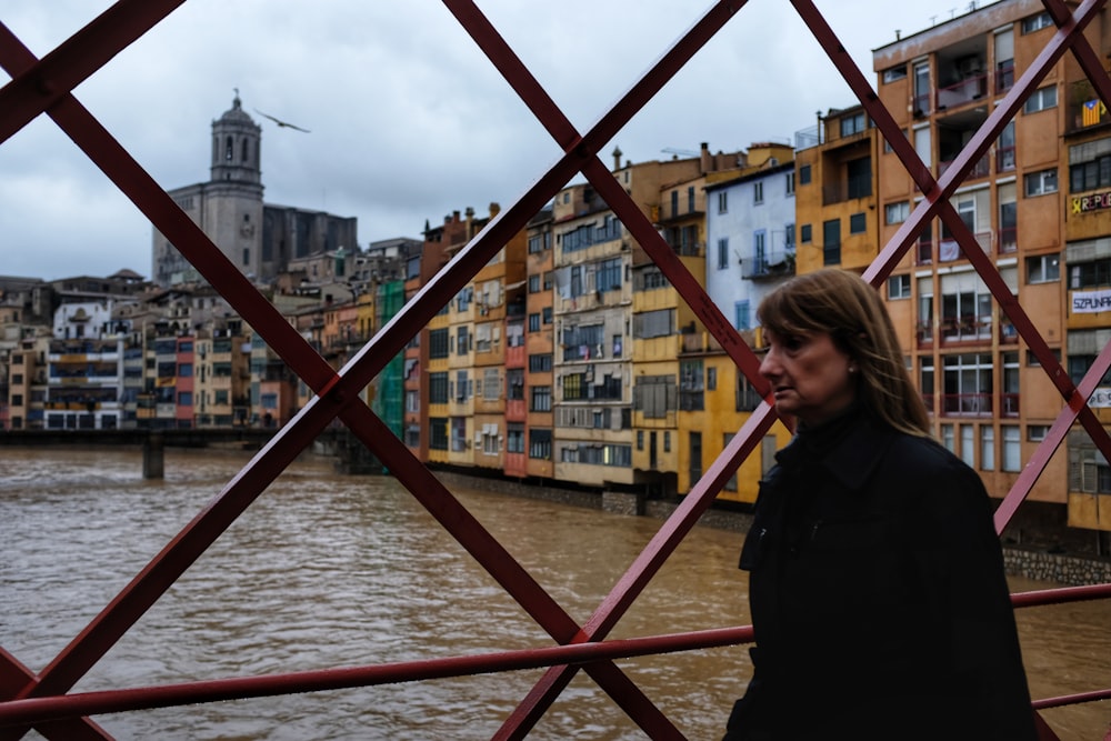 woman in black jacket standing beside red metal railings