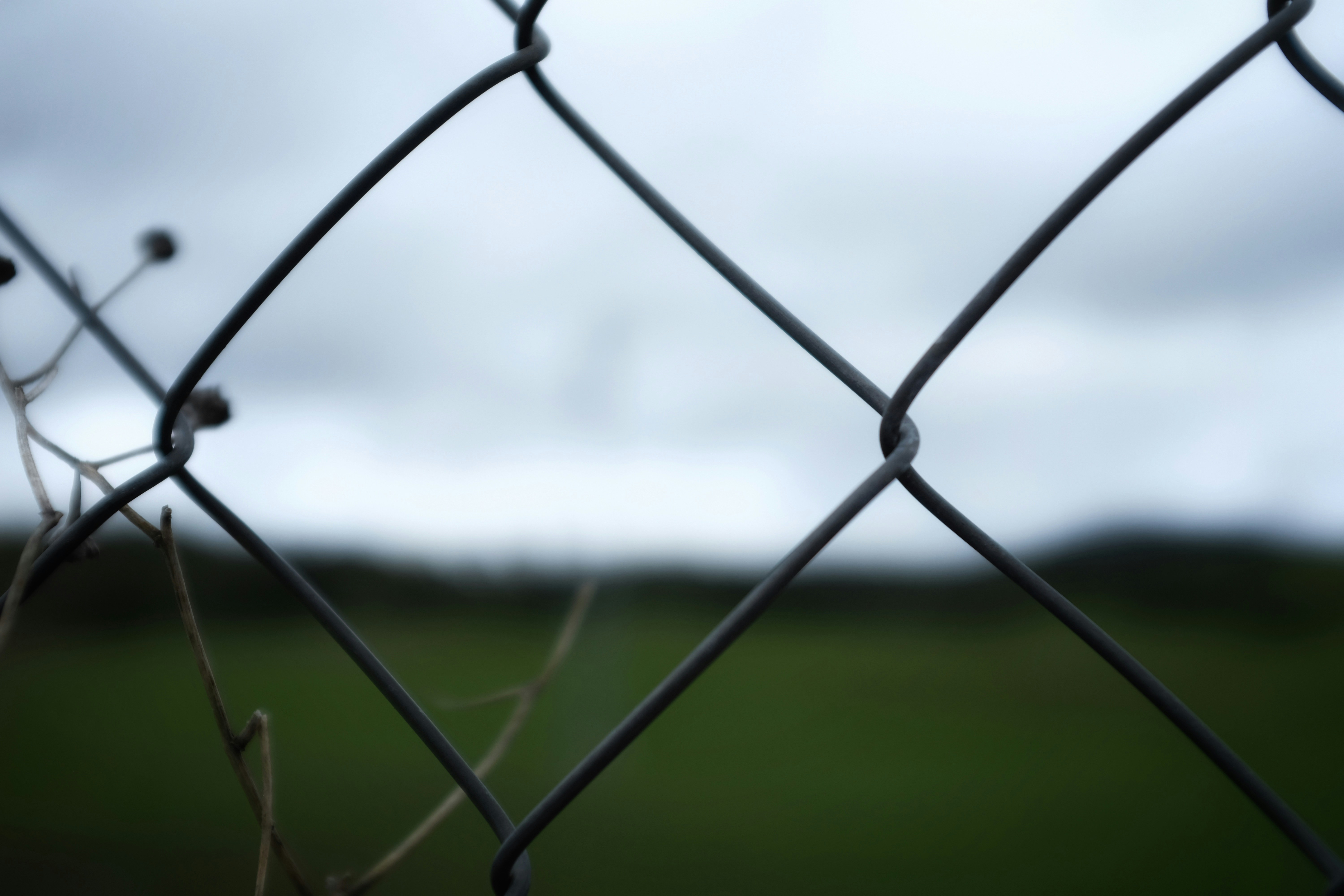 grey metal fence with green grass field in distance