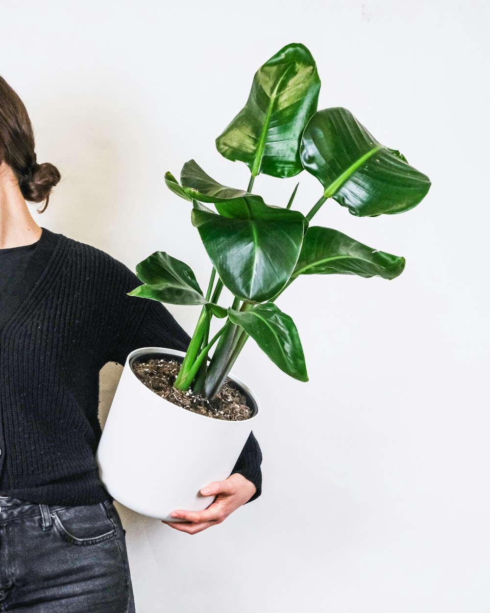 Femme en pull noir tenant une plante verte