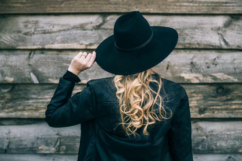 mulher na camisa preta de manga comprida e chapéu preto
