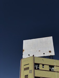 Workers restoring an old, weathered billboard with fresh paint and new lighting.