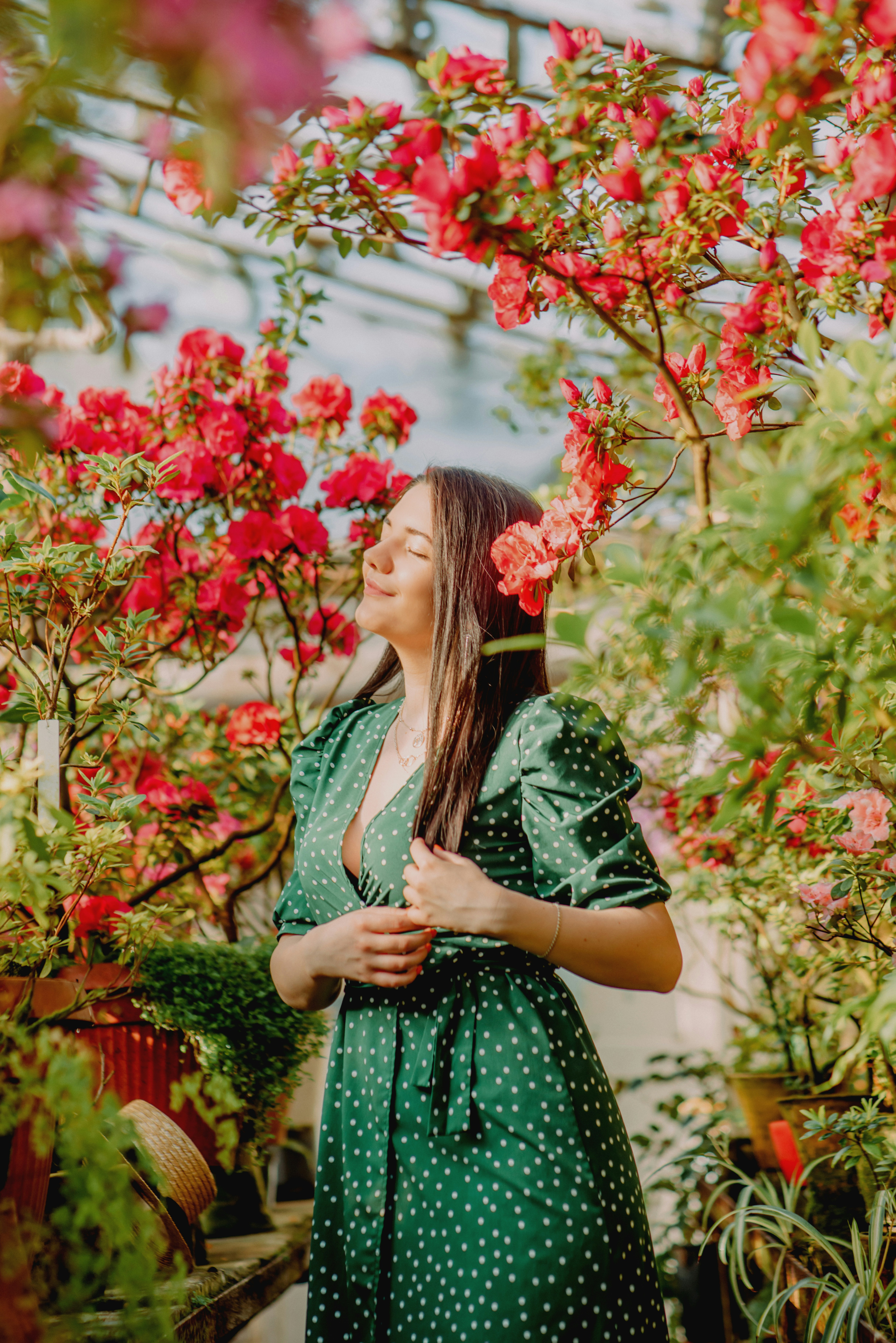 woman in green and black dress standing near red flowers during daytime