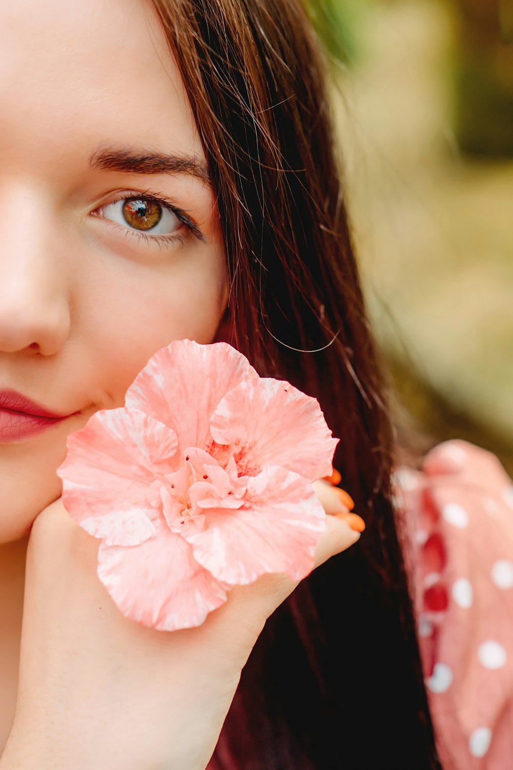 woman holding pink hibiscus flower