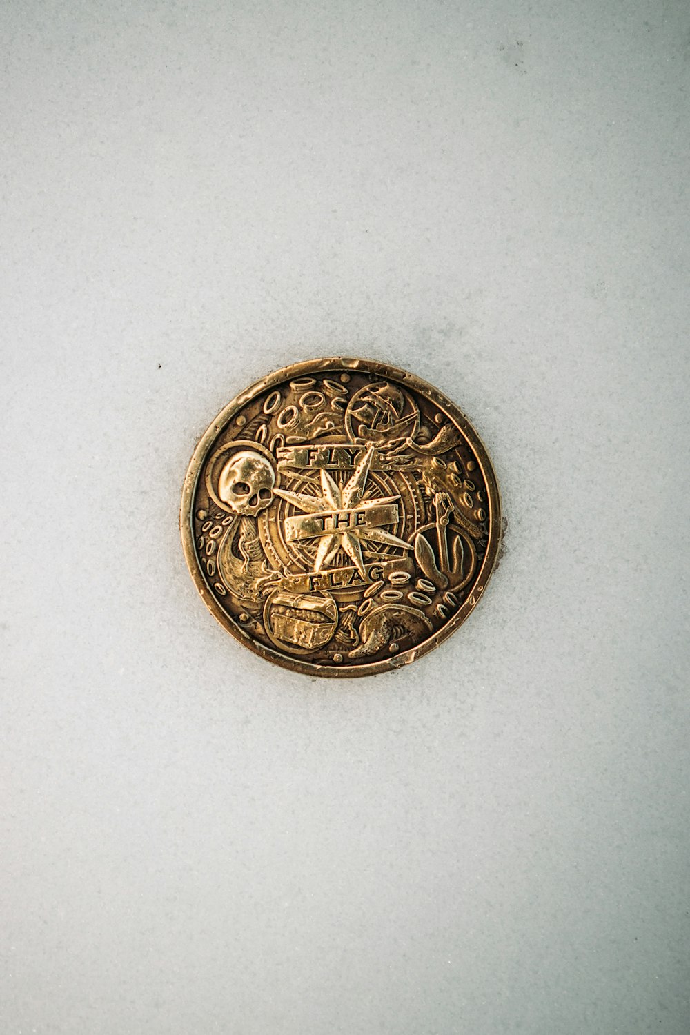 gold round coin on white surface