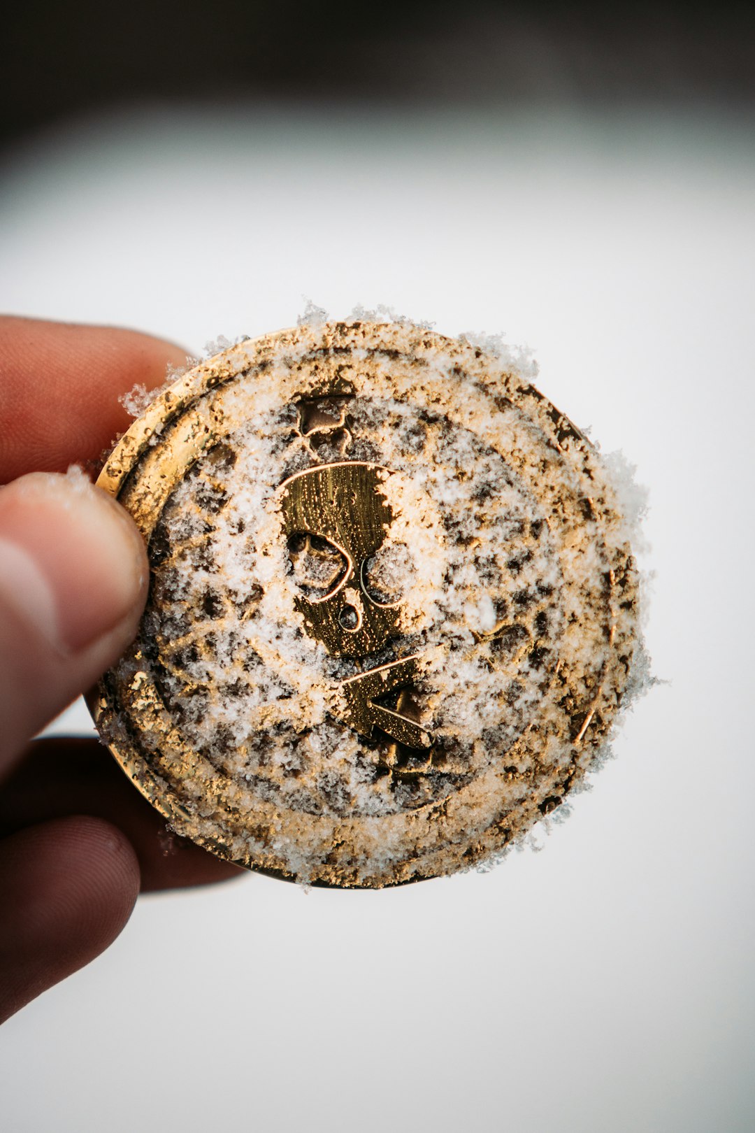 gold round coin on persons hand