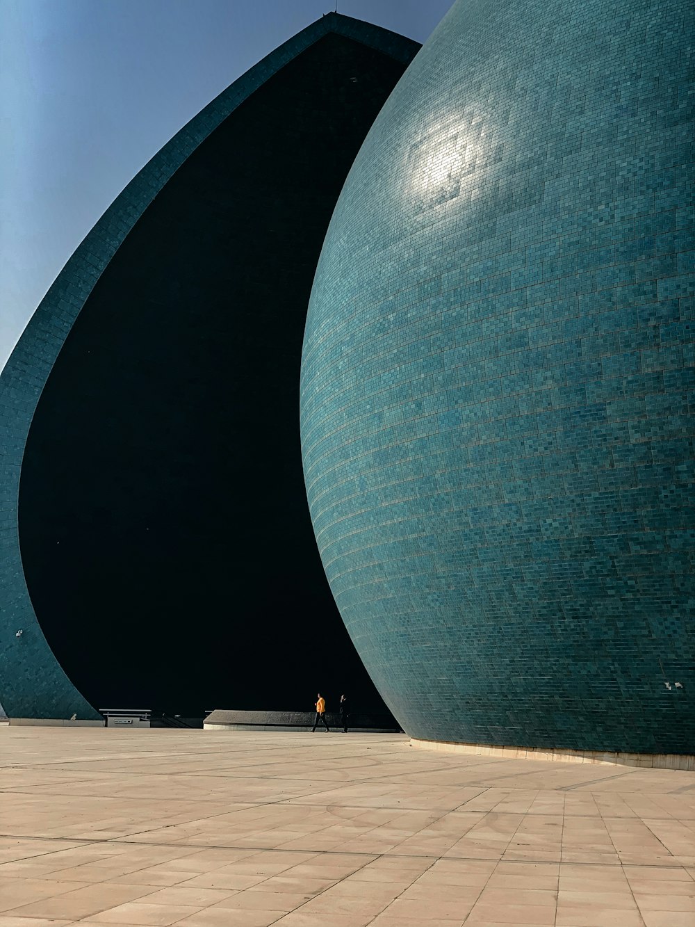 man in black shirt and blue denim jeans standing near black round structure