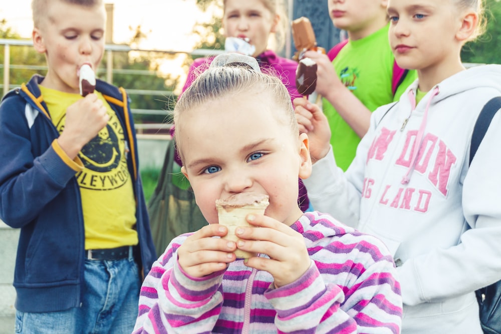 boy in white and pink striped long sleeve shirt holding ice cream