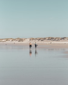 2 person walking on beach during daytime