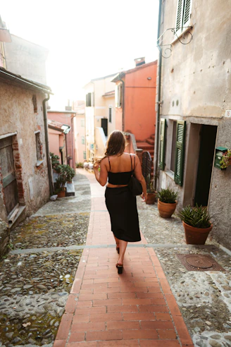 woman in black dress walking on sidewalk during daytime